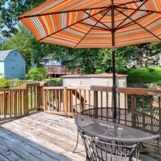 A sunny backyard deck with patio furniture and a colorful umbrella, perfect for relaxing outdoors.