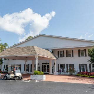 A spacious clubhouse with a grand entrance, featuring a golf cart parked outside.