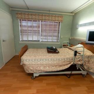 A hospital room with a single bed, television, and window.