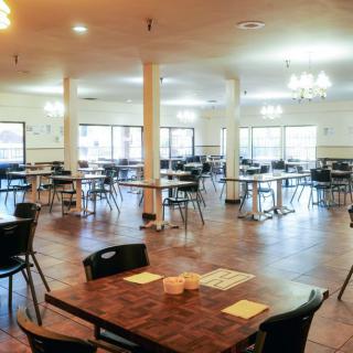 An empty dining hall with neatly arranged tables and chairs.
