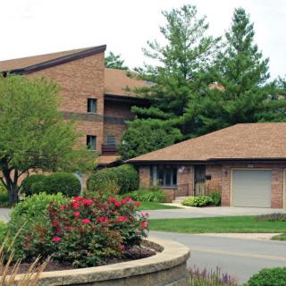 A brick building surrounded by lush greenery and a well-maintained garden.