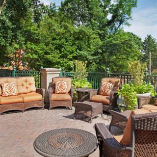 A cozy outdoor patio with comfortable seating surrounded by lush greenery.