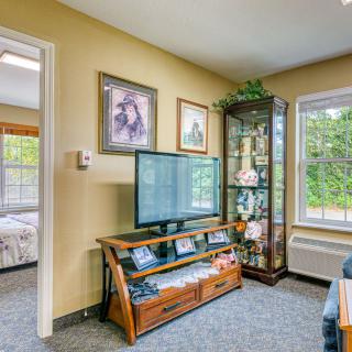 A cozy living room with a television, framed pictures on the wall, and a display cabinet filled with decorative items.