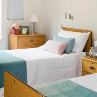 A cozy, minimalist bedroom with twin beds and wooden furniture, featuring a soft color palette.