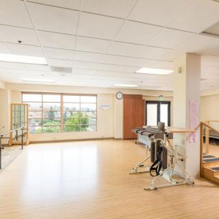 A spacious rehabilitation center with therapy equipment and large windows providing ample natural light.