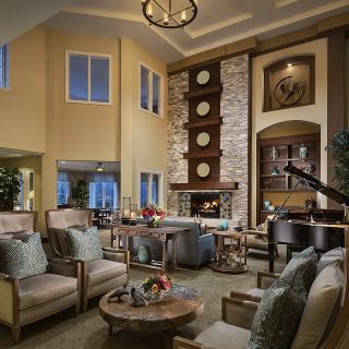 A cozy and elegant living room with a high ceiling, featuring a fireplace and a grand piano.