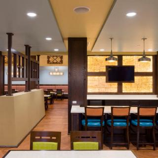 Modern restaurant interior with colorful seating and a mounted television.
