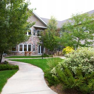 A scenic walkway leading to a residential building surrounded by lush greenery and trees.