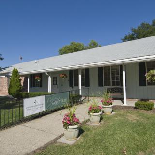 A small, single-story building with a garden and walkway under a clear blue sky.