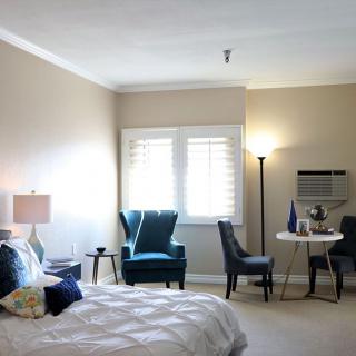 A cozy bedroom with comfortable seating, a small table, and soft lighting.