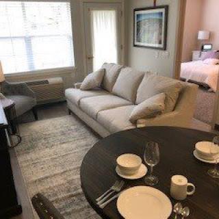 A cozy apartment living room with a sofa and dining area set for a meal.