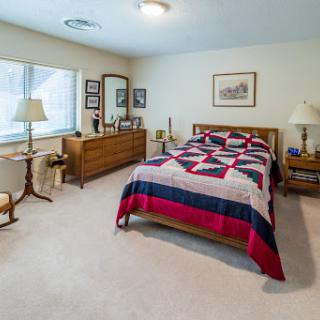 A cozy and well-furnished bedroom featuring a quilted bedspread and warm lighting.