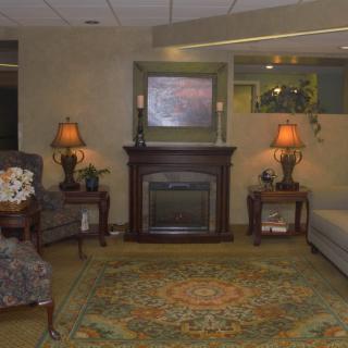 A cozy living room with a fireplace, armchairs, and decorative lamps.