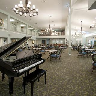 An elegant dining area with a grand piano and chandeliers.