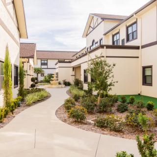 A modern residential apartment complex with well-maintained landscaping and a winding pathway.