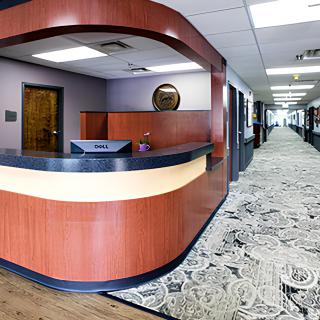 Modern office reception area with a desk and carpeted hallway.