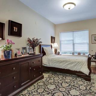 A cozy bedroom with a bed, wooden dresser, and decorative elements.