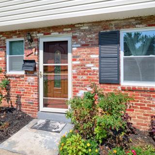 A front view of a brick house with a glass door and surrounding greenery.