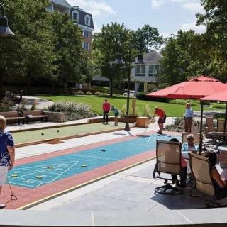 A group of people enjoying outdoor games at a recreation area with bocce and shuffleboard.