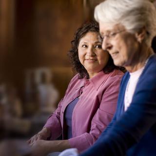 Two women having a conversation indoors, one smiling.