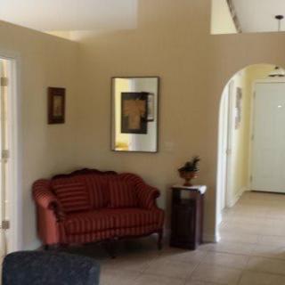 A cozy living room area featuring a red striped sofa, wall art, and an archway leading to the hallway.