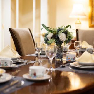 An elegantly set dining table with fine china and a floral centerpiece, perfect for a formal gathering.