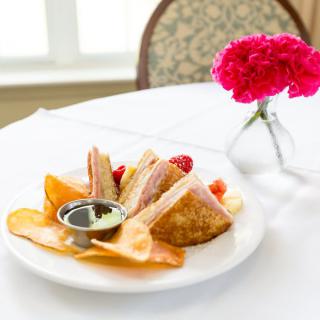 A plate of dessert pastries with dipping sauce, elegantly presented on a table with a floral centerpiece.