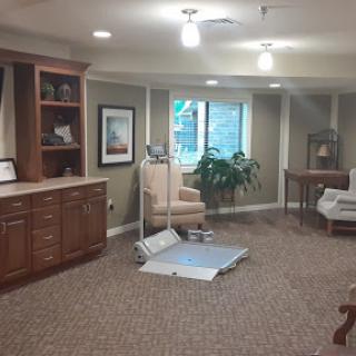 A well-lit rehabilitation room featuring comfortable seating, exercise equipment, and a view of nature.