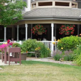 A beautifully landscaped garden with blooming flowers and hanging baskets on a porch.