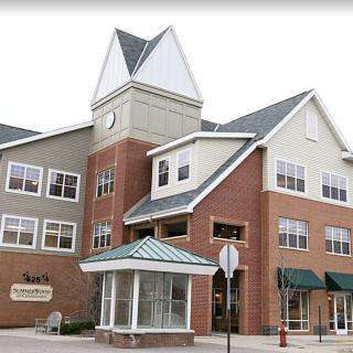 A multi-story building featuring a clock tower and brick facade, with storefronts on the ground level.