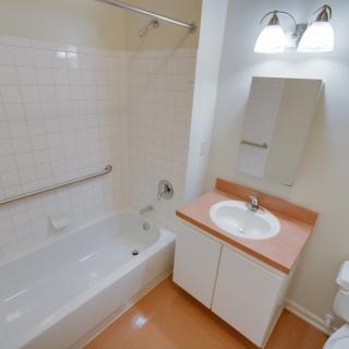 A clean and simple bathroom with a bathtub, sink, and vanity.