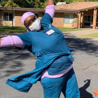 A joyful healthcare worker celebrating in scrubs outside.