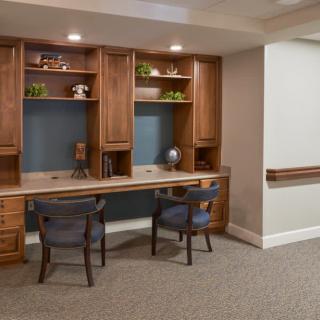A cozy office space with wooden furniture and decorative shelving.