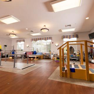 A bright and spacious physical therapy room equipped with various exercise devices for rehabilitation.