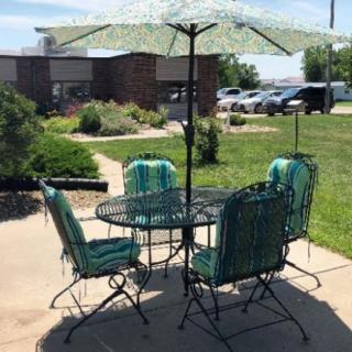 A patio set with a table, chairs, and an umbrella in a garden setting.