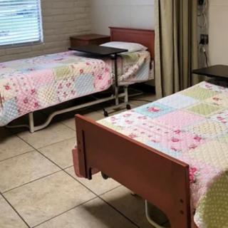 A hospital room with twin beds featuring quilted bedspreads and a curtain divider.