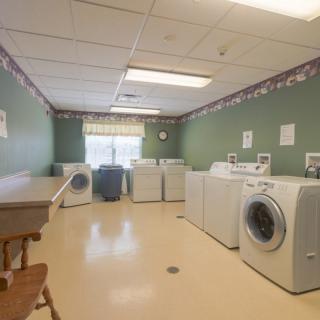 A spacious laundry room with multiple washing machines and dryers.
