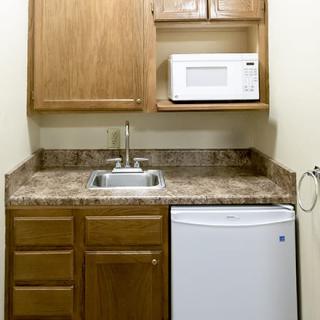 A compact kitchen setup with a microwave, sink, and mini fridge.