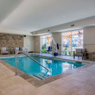 An indoor swimming pool with seating and large windows providing natural light.