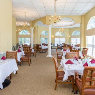A beautifully set dining area in a restaurant with white tablecloths and elegant seating.