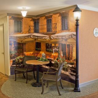A cozy indoor cafe setting with a mural of a street scene, featuring a table and chairs beneath a faux street lamp.