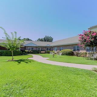 A serene view of a building surrounded by lush greenery and a clear blue sky.