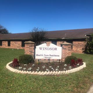 A well-maintained entrance sign for Windsor, featuring a flowerbed and clear blue skies.