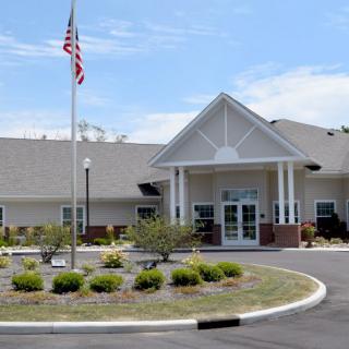 A building with an American flag and a landscaped entrance under a blue sky.