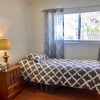 A cozy bedroom with a single bed, patterned bedding, and a lamp on the nightstand.