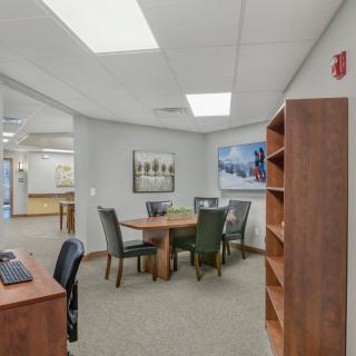 A spacious office meeting room with a wooden table, chairs, and shelves.