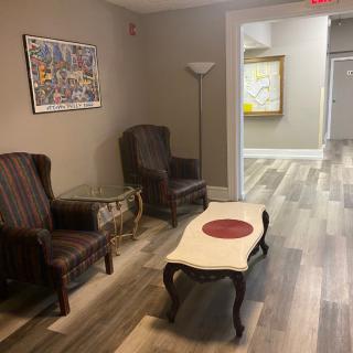 A cozy waiting area with chairs and a table, featuring artwork and flooring.