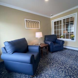 A cozy living room with blue armchairs and a lamp by the window.
