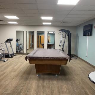 A multi-purpose indoor room featuring gym equipment and a pool table.