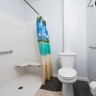 A modern bathroom featuring a shower, toilet, and a vibrant beach-themed shower curtain.